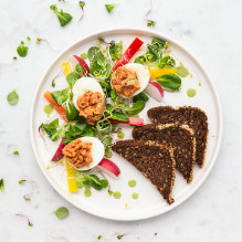 breakfast in a box diet with a low glycemic index - eggs stuffed with dried tomato paste, radish and pepper particles, yoghurt and basil sauce, bread with a low glycemic index
